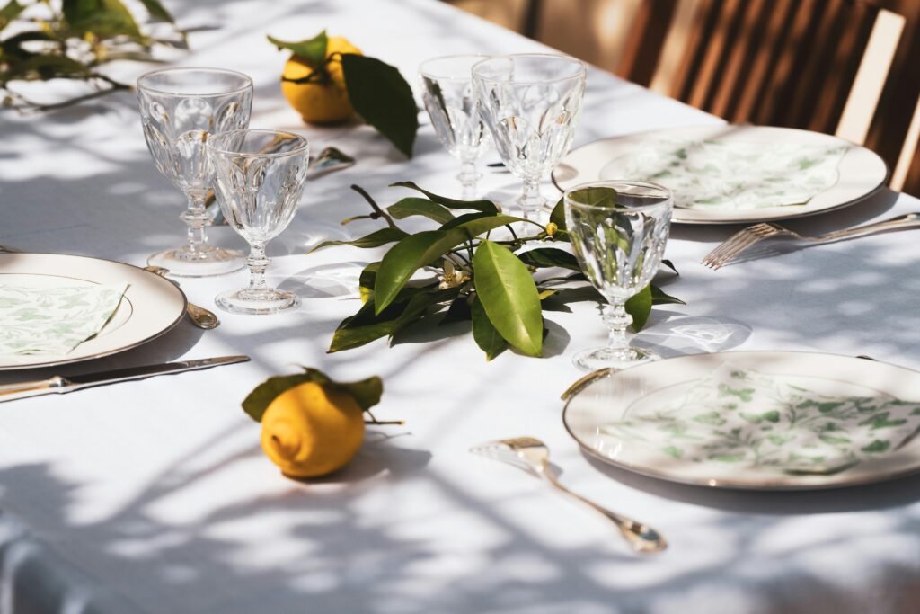 A picturesque scene of a table set up outdoors in the daylight, adorned with gleaming wine glasses, evoking a sense of refined elegance and the promise of a delightful dining experience.