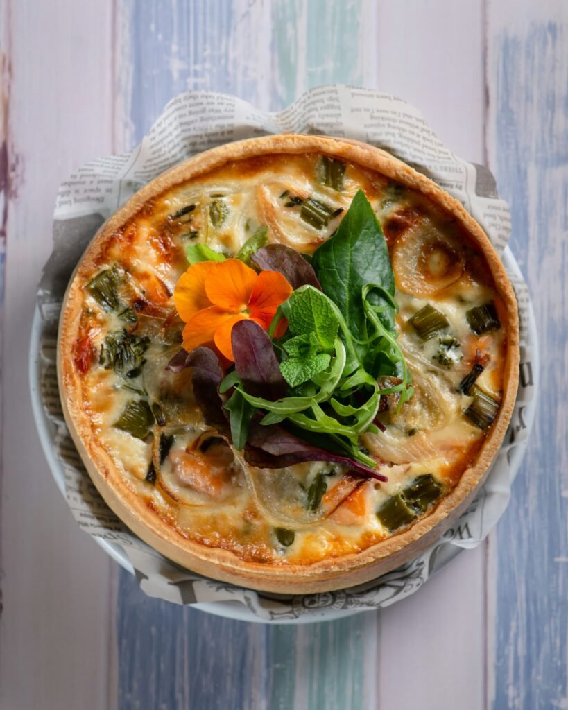 A freshly baked vegetable quiche with a golden crust, perfect for pairing with a delicate Pinot Noir Rose wine