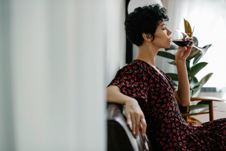 Woman sitting and drinking a glass of red wine at home
