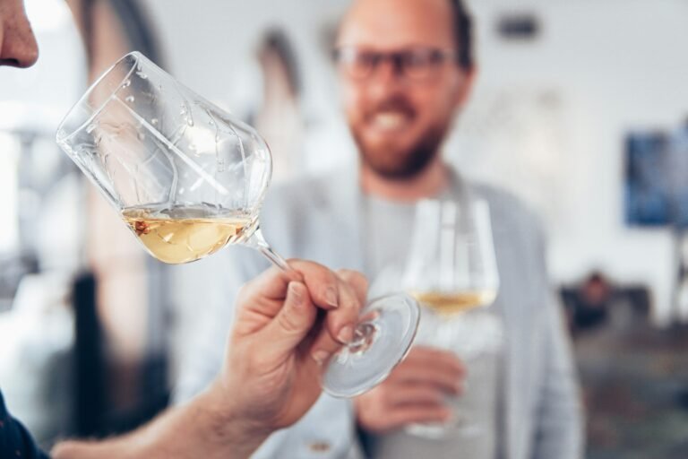 Person sniffing a glass of white wine during a wine tasting event