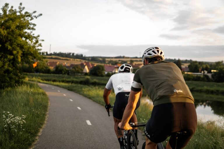 Two friends cycling on a road in the middle of the mountains, enjoying a scenic outdoor adventure.