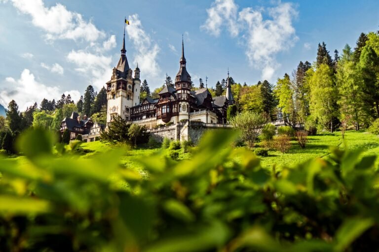 Beautiful Peles Castle surrounded by lush greenery in Romania.