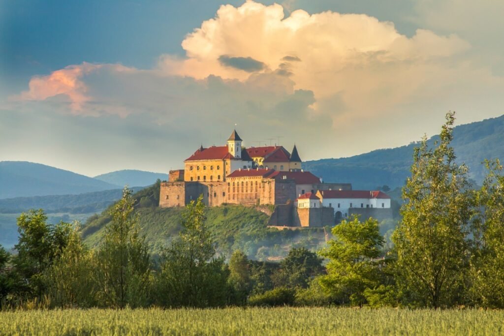Historic castle on a hill in Transcarpathia with scenic mountains in the background.