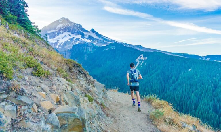 A person doing a trail run on top of a mountain with a breathtaking view of the landscape below.