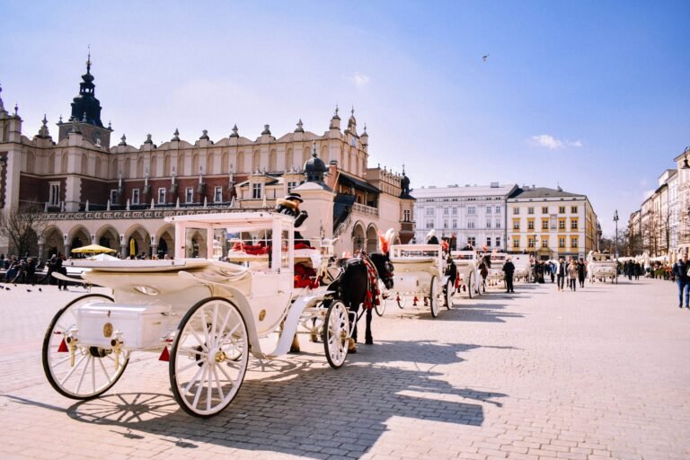 Horse-drawn carriages in the main square of Krakow, Poland, with historic buildings in the background