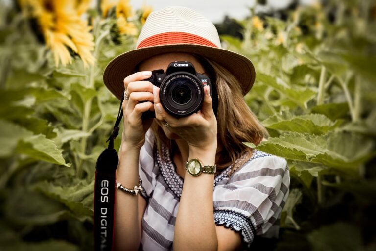 Woman taking a photograph with a Canon camera in a field of sunflowers