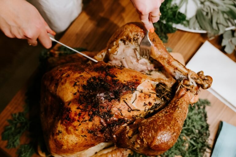 Close-up of a person carving a perfectly roasted chicken on a wooden table