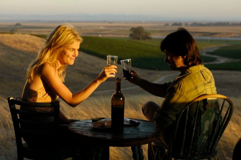 A scene from the movie Bottle Shock where a girl and a guy are toasting with wine at sunset.