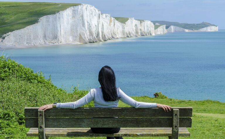 Woman sitting on a bench overlooking the white cliffs and the ocean.