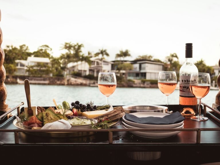 Table set with glasses of rosé wine and appetizers by the waterfront.