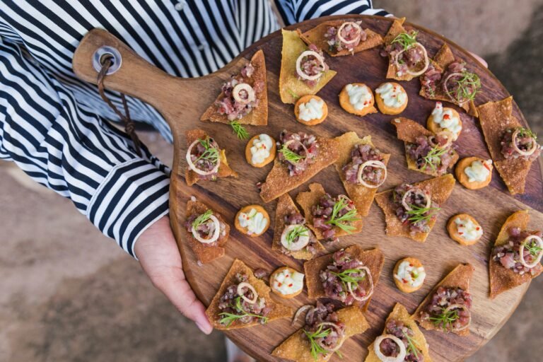 A wooden serving board with a variety of elegant canapés, perfect for a gourmet gathering.