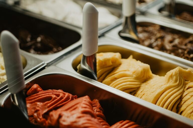 Assorted flavors of gelato in metal containers at an ice cream shop