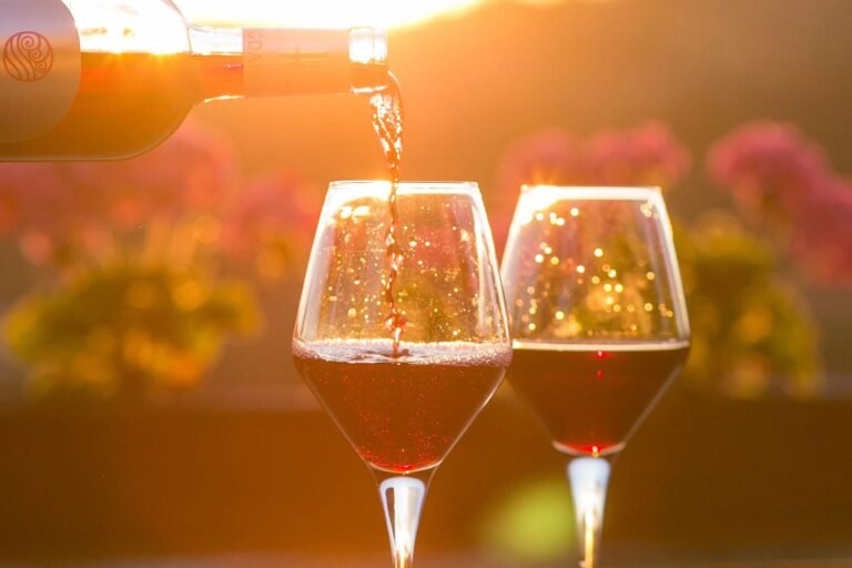 Wine being poured into glasses at sunset, creating a romantic and picturesque scene.