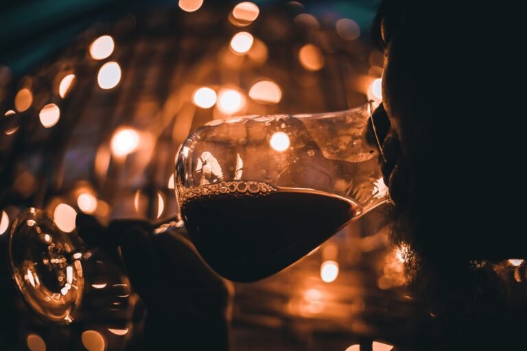 Red Wine at Night with a Person Sniffing the Aroma, Background Lights Creating an Atmosphere