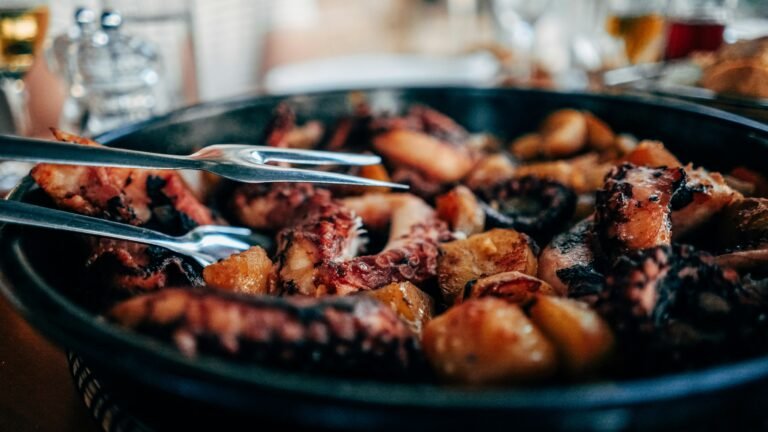 Grilled octopus with potatoes in a black pan, ready to be served.