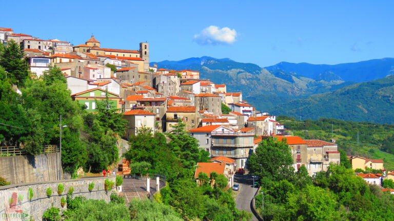 Panoramic view of the picturesque village of Santa Domenica Talao, Italy, with colorful houses and mountainous background.