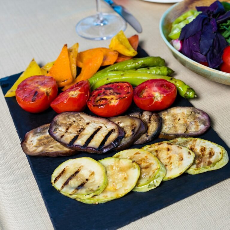 A colorful plate of grilled vegetables including tomatoes, aubergine, courgettes, and asparagus, seasoned and charred to perfection.