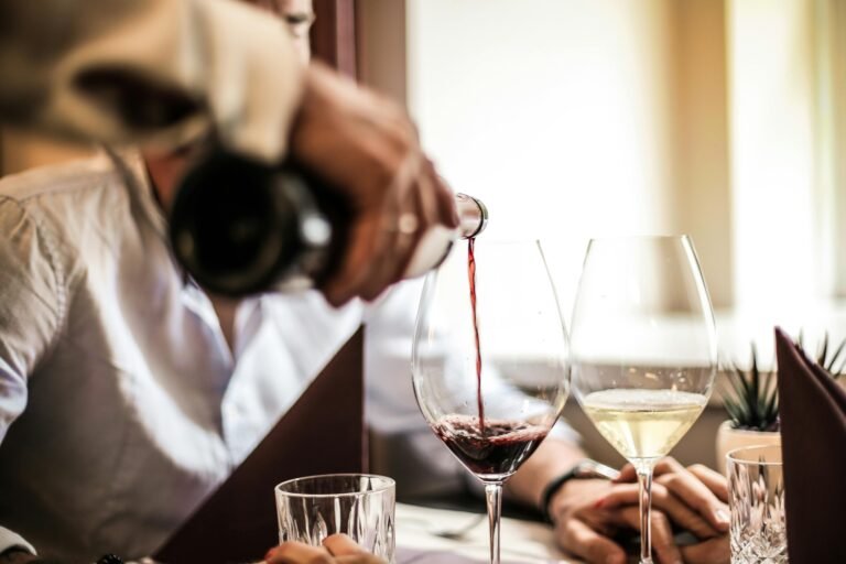 A close-up of red wine being poured into a glass during a wine tasting event.