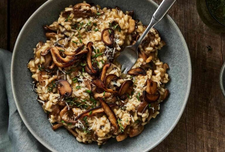 Creamy mushroom risotto topped with sautéed mushrooms and fresh herbs in a bowl.