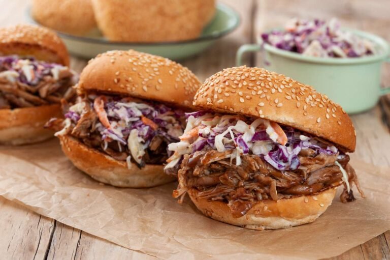 Pulled pork sandwiches topped with creamy coleslaw in sesame seed buns.