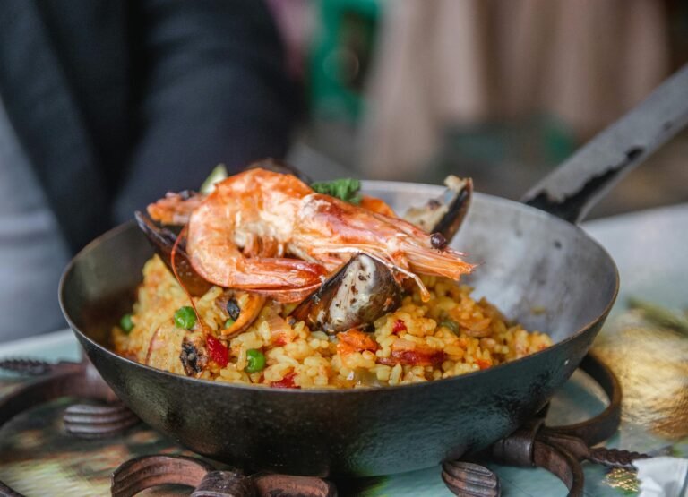 Delicious seafood paella in a black pan with shrimp, mussels, and vegetables.