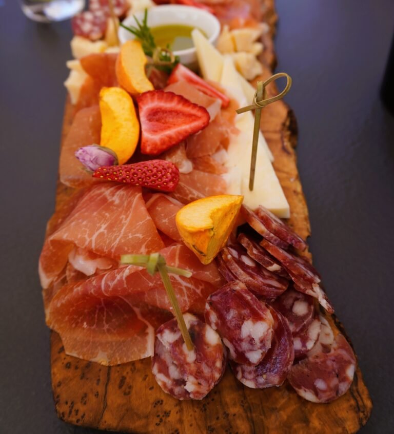 A beautifully arranged cheese and cold meat board featuring a variety of Istrian cheeses, cured meats, and dried fruits, offering a rustic and gourmet dining experience, perfect for wine pairing.