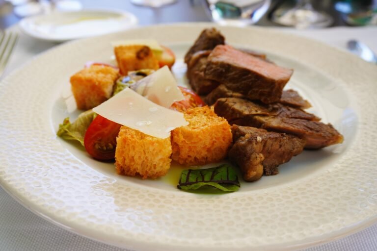 A gourmet dish featuring succulent steak slices paired with croutons, tomatoes, and parmesan in a fine dining restaurant in Istria.