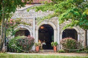 Beautiful stone winery building surrounded by lush greenery at a traditional Istrian estate.