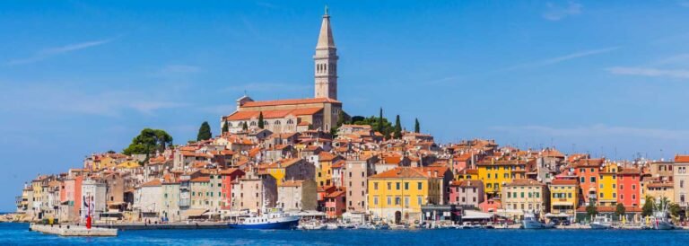 Colorful coastal town of Rovinj with a prominent church tower overlooking the Adriatic Sea.