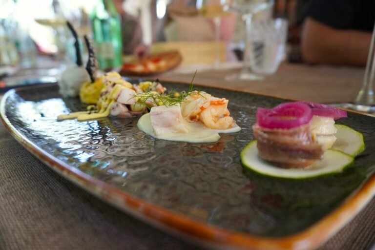 Beautifully presented seafood plate with shrimp, octopus, and fish served with garnishes at a gourmet restaurant.