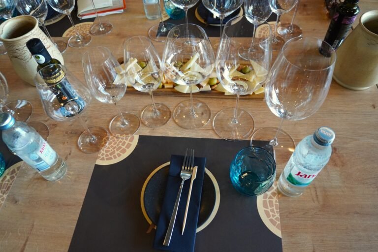 Elegant wine tasting setup with empty wine glasses, olive oil bottles, water, and cheese, ready for a wine masterclass.