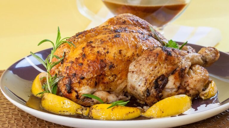 Succulent roast chicken garnished with lemon wedges and fresh rosemary on a serving plate