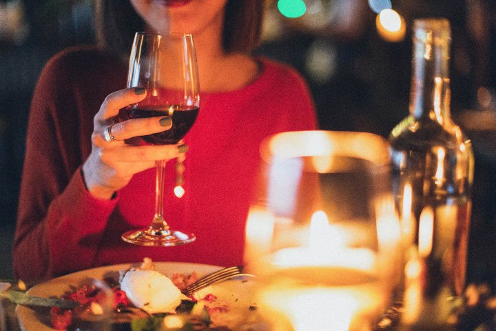 Woman enjoying a glass of red wine at a candlelit dinner