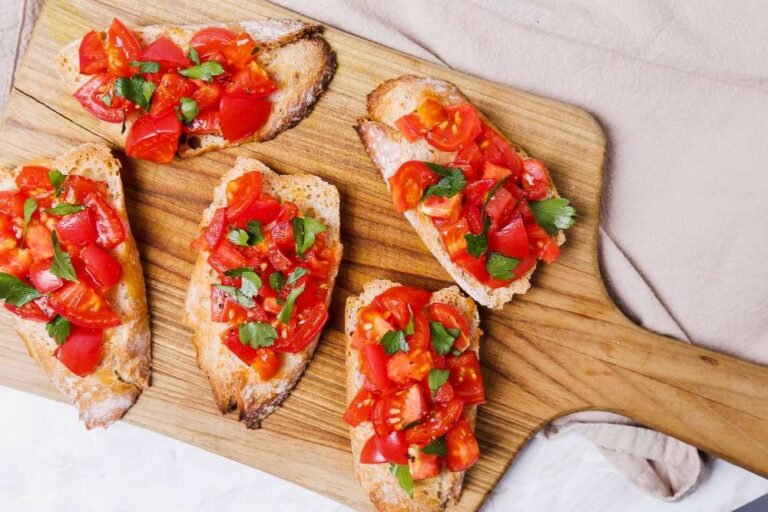 Italian bruschetta with fresh tomatoes, parsley, and olive oil on a wooden board.