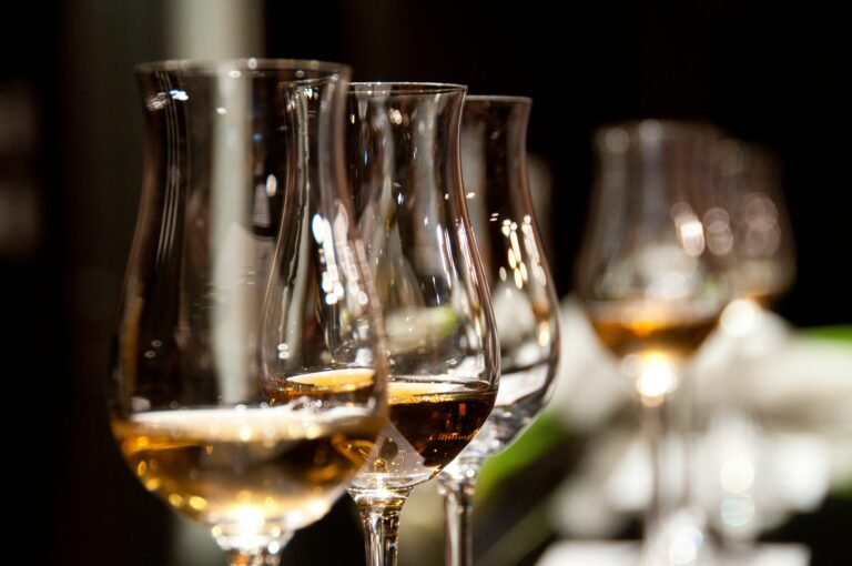 Row of wine glasses filled with white wine, ready for a tasting session in a dimly lit room.