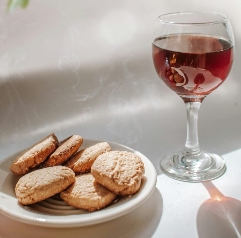 A glass of wine served with a plate of cookies, creating a cozy and warm atmosphere for a relaxing moment.