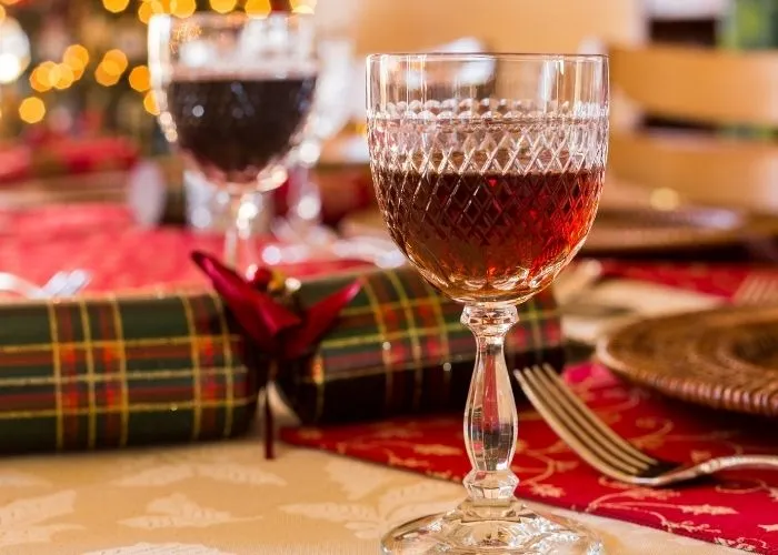 Elegant crystal glass filled with sherry on a Christmas table setting, decorated with a tartan holiday cracker and red tablecloth, embodying a festive holiday atmosphere.