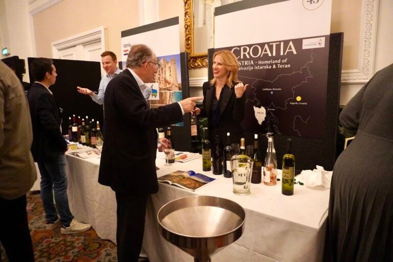 Wine representatives engaging with visitors at a Vinistra booth showcasing Croatian wines and Istrian heritage during a wine event.