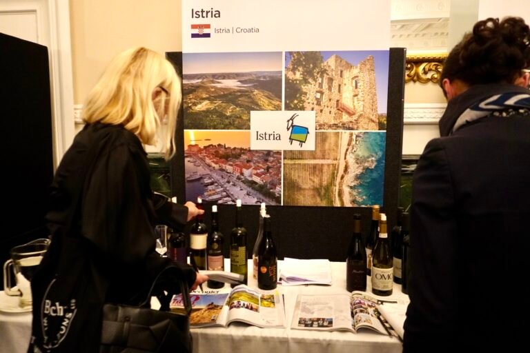 Visitors exploring wine bottles and brochures at the Istria booth, showcasing Croatian culture and landscapes during a Vinistra event.