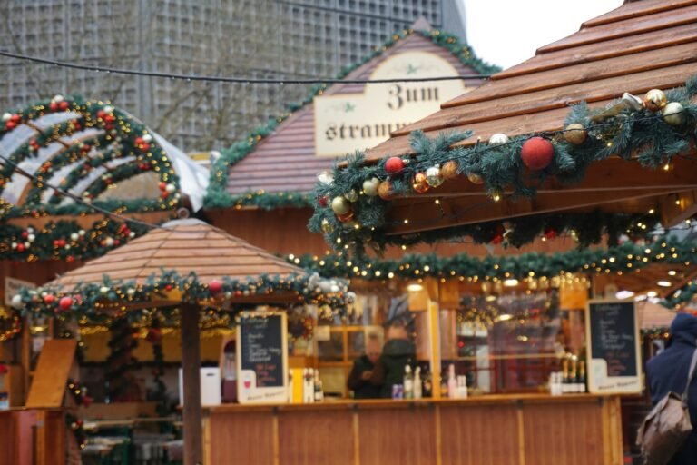 Festive Christmas market stalls decorated with garlands, lights, and ornaments, creating a cozy holiday atmosphere in an outdoor setting