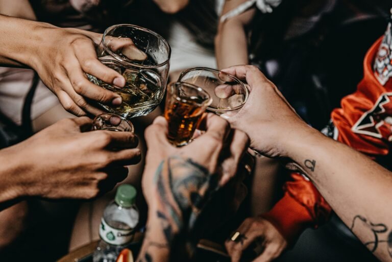 A group of friends toasting with whiskey glasses and shot glasses during a celebratory moment.