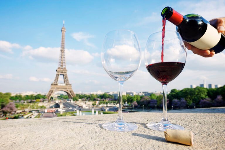 A romantic evening in Paris featuring a glass of red wine with a stunning view of the Eiffel Tower, capturing the essence of French culture and fine dining.