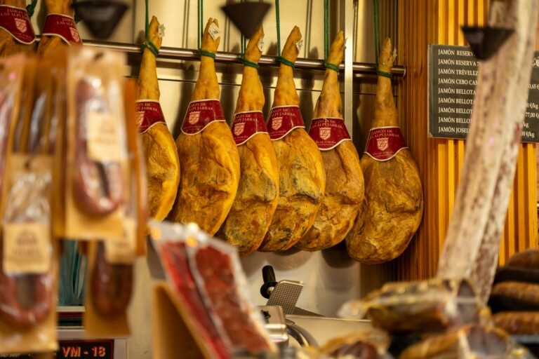 Legs of cured Iberian ham hanging in a Spanish delicatessen, showcasing traditional charcuterie ready to be sliced for gourmet enjoyment.