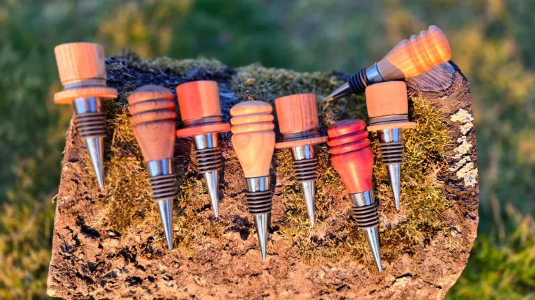 Handcrafted wooden wine stoppers with metal tips displayed on a tree bark outdoors in natural sunlight.