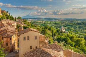 Scenic view of Montepulciano village and the Tuscan countryside with vineyards and rolling hills under a bright summer sky